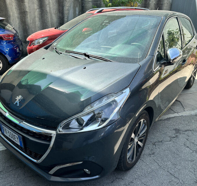 Front-left view of a dark gray Peugeot car parked in a lot beside a blue car and a red car behind it.