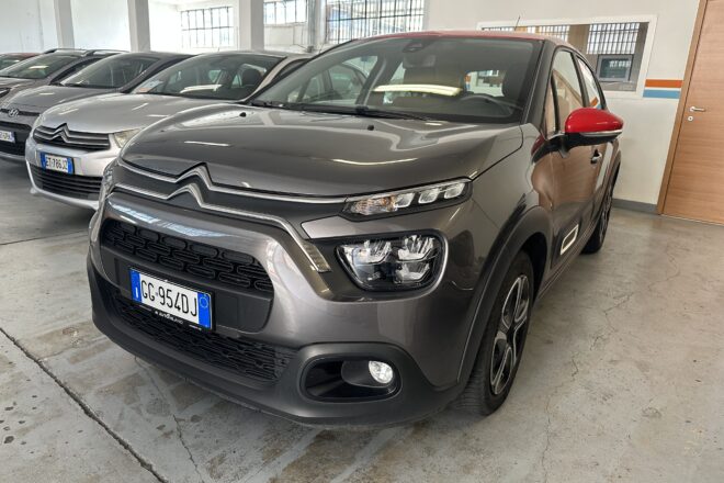 Grey Citroën SUV in a car showroom with red side mirror and other cars lined up in the background.
