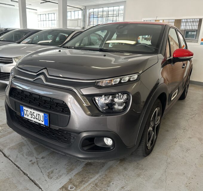 Grey Citroën SUV in a car showroom with red side mirror and other cars lined up in the background.