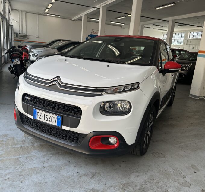White Citroën SUV with red accents parked in an indoor garage, other cars lined up behind.