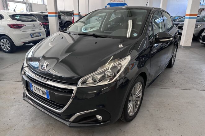 Front-left view of a shiny black Peugeot in an indoor car showroom with other cars in the background.