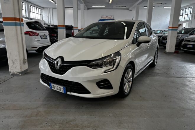 Front three-quarter view of a white Renault in an indoor parking garage with concrete pillars and other cars nearby.