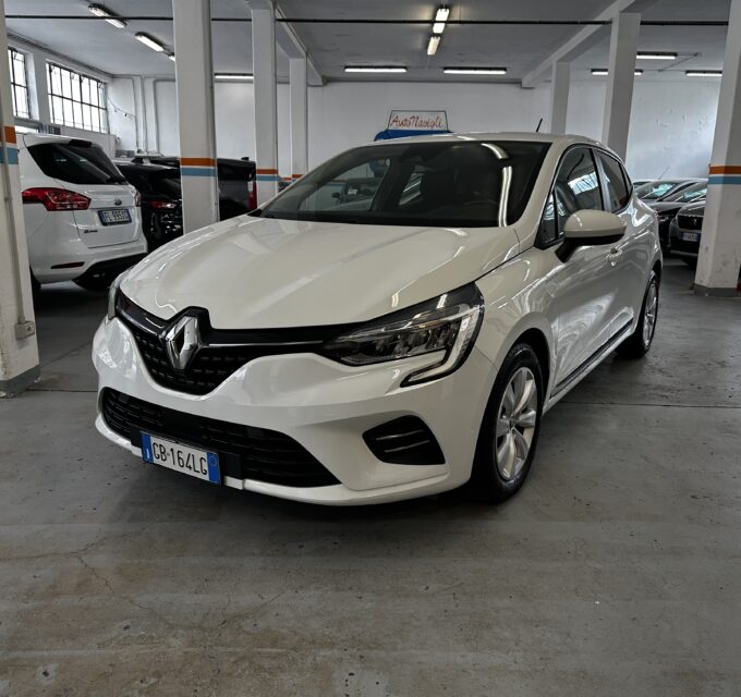 Front three-quarter view of a white Renault in an indoor parking garage with concrete pillars and other cars nearby.