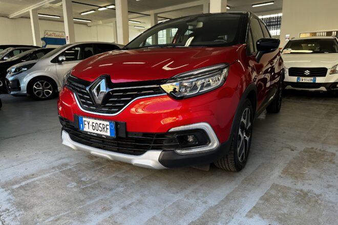 Red Renault SUV in a dim indoor parking garage, with silver and white cars nearby and concrete pillars around.
