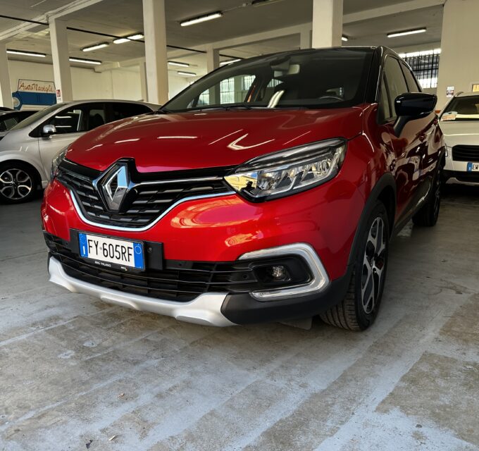 Red Renault SUV in a dim indoor parking garage, with silver and white cars nearby and concrete pillars around.