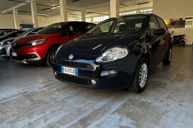 Indoor parking garage with a blue Fiat in the foreground and a red car beside it under concrete pillars
