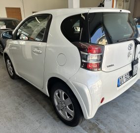 White Toyota SUV parked indoors beside a gray car, showing rear three-quarter view and taillights.