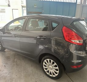 Gray hatchback parked indoors, showing the rear passenger side with the red tail light.