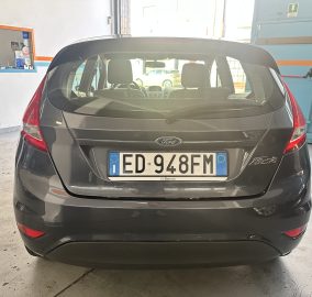 Rear view of a dark gray Ford Fiesta in a service bay, license plate ED 940FM clearly visible