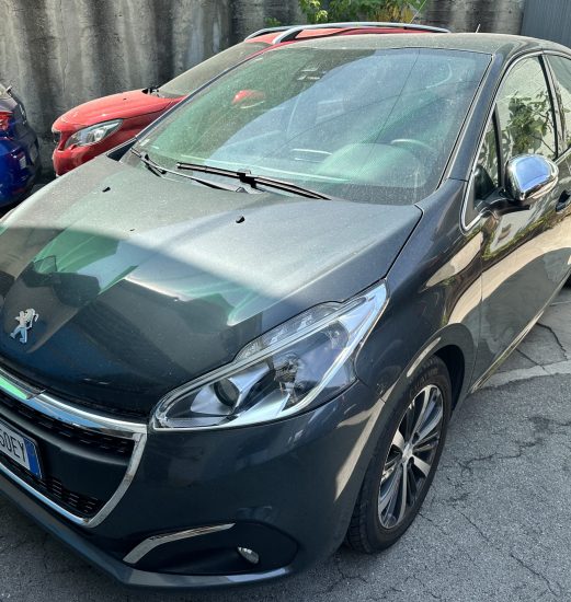 Front-left view of a dark gray Peugeot car parked in a lot beside a blue car and a red car behind it.