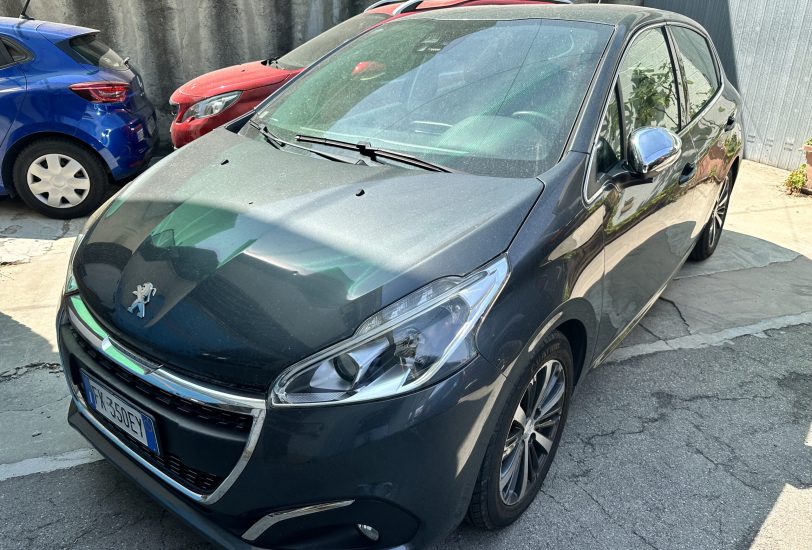 Front-left view of a dark gray Peugeot car parked in a lot beside a blue car and a red car behind it.