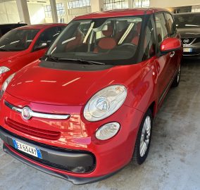 Red Fiat SUV parked indoors in a showroom, angled toward the camera with other cars in the background.