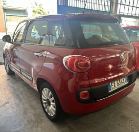 Red Fiat 500X SUV parked indoors, rear view visible with a second red car beside it in a garage setting.