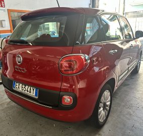 Rear three-quarter view of a red Fiat 500L parked inside a garage, showing the tail lights and European license plate (EX 63ZAY).