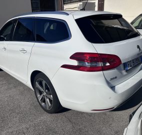 Rear three-quarter view of a white Peugeot SUV parked in a lot, with dark-tinted rear windows and visible tail light.