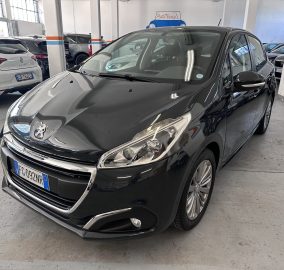 Front-left view of a shiny black Peugeot in an indoor car showroom with other cars in the background.