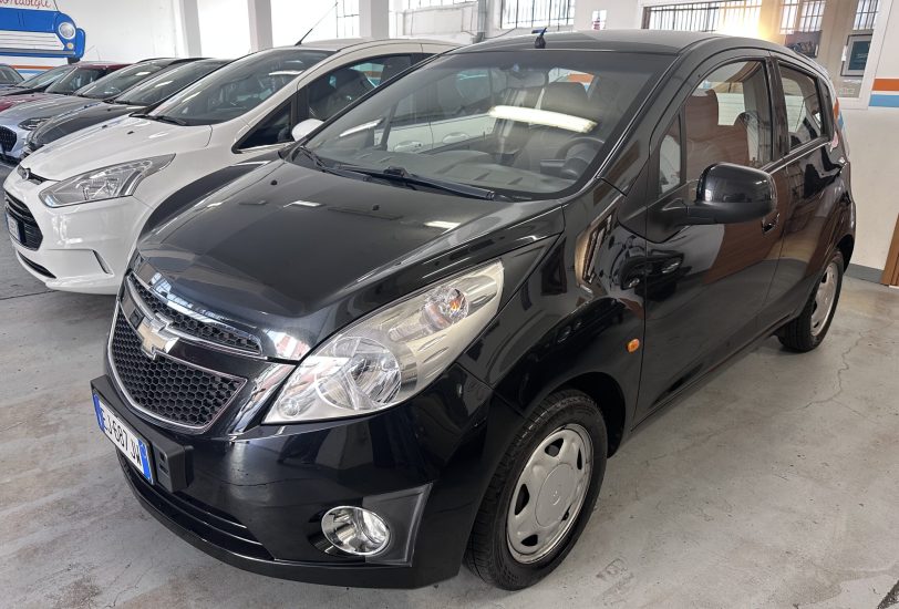 Front quarter view of a black SUV in a car dealership showroom with white and gray cars lined up in the background.