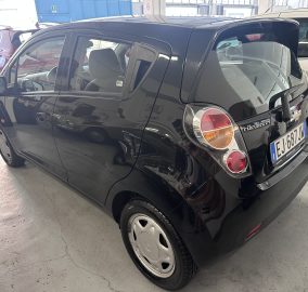 Rear three-quarter view of a black Chevrolet hatchback parked indoors among other cars, with visible tail lights and license plate