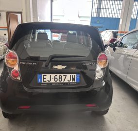 Rear view of a black Chevrolet Spark LS in an indoor garage; visible tail lights, badge, and Italian license plate EJ 687 JW.