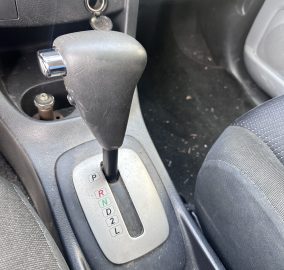 Close-up of a car's center console showing the automatic gear selector in Park with the PRND21L indicator labels.