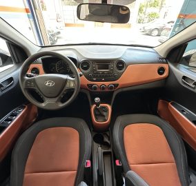 Interior of a car viewed from the back seat with brown seats, black dashboard, steering wheel, and gear shift visible.