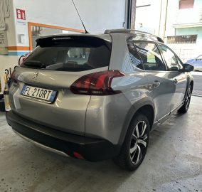 Rear and side view of a grey Peugeot SUV parked in a dim garage, showing the tail lights and license plate partially visible