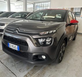 Grey Citroën SUV in a car showroom with red side mirror and other cars lined up in the background.