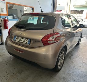 Silver Peugeot 208 hatchback parked in a workshop, showing its rear and right side with Italian license plate EP-870CS