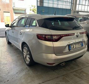 Rear three-quarter view of a white Renault Megane SUV parked inside a garage, with another car beside it and a visible Italian license plate (G A 277FN).