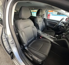 Interior view of a car showing front driver and passenger seats with black fabric upholstery and white stitching, dashboard and steering wheel visible, door open.