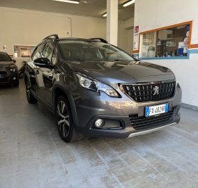 Gray Peugeot SUV parked indoors in a garage, with a striped pillar and a service window in the background.
