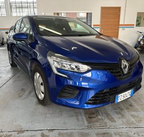 Blue three-quarter front view of a shiny SUV inside a showroom/garage with other parked cars and a wooden door in the background.