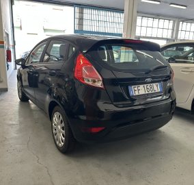 Black Ford hatchback viewed from rear in a service bay, Italian plate EF 168LY, with a white car beside it in a garage setting