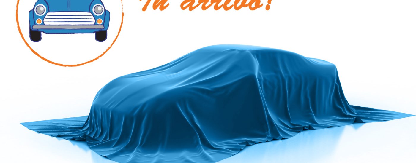 Blue car under a satin cover on a white studio background, with orange 'In arrivo!' text and a circular logo featuring a blue car labeled 'AutoNawili'.