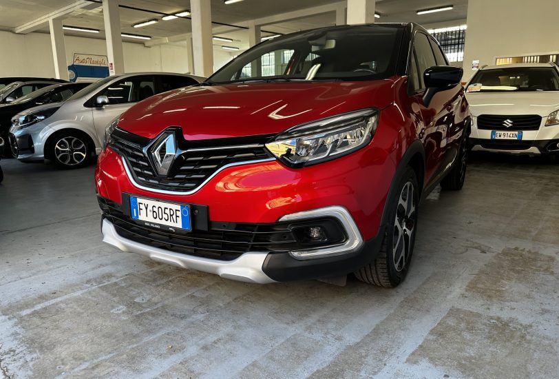 Red Renault SUV in a dim indoor parking garage, with silver and white cars nearby and concrete pillars around.