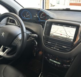 Interior of a car cockpit with steering wheel, digital gauges, and a navigation touchscreen visible in the center console.