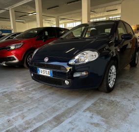 Indoor parking garage with a blue Fiat in the foreground and a red car beside it under concrete pillars