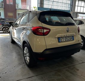 Beige Renault Captur rear view parked in a covered garage with other cars nearby and license plate EY 052AH visible.