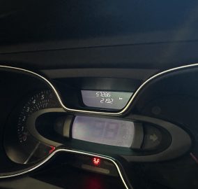 Close-up of a car dashboard with an illuminated instrument cluster; odometer reads 57,286 km.