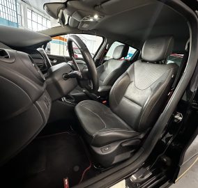Interior of a black car showing front seats with 'RS' logo on the headrests and a leather-wrapped steering wheel