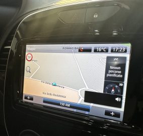 In-car GPS navigation screen showing a map with street names (Via Della Resistenza), time 17:23 and 16°C.