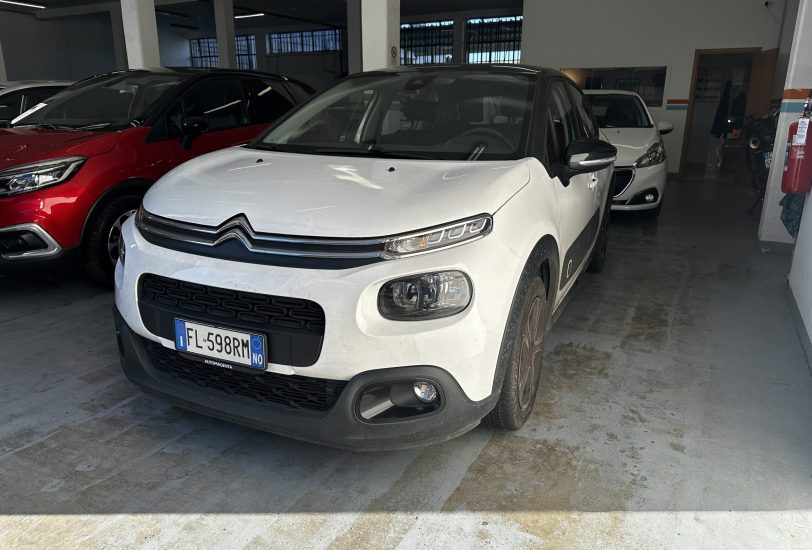 White Citroën SUV in a showroom, with a red car to the left and a white car in the background inside a dealership.